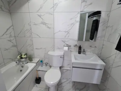 a white bathroom with a toilet and a sink at 607 Odean - Luxury Ocean Escape in Strand