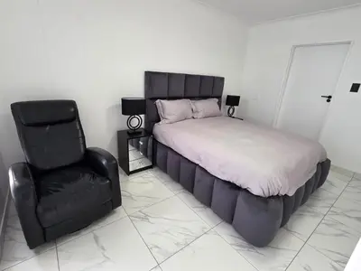 a bedroom with a bed and a black chair at 607 Odean - Luxury Ocean Escape in Strand