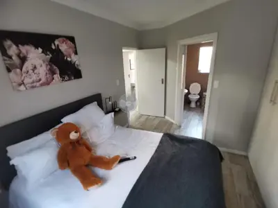 a teddy bear sitting on top of a bed at Cosy 3 bedroom in Cape Town
