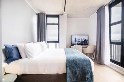 a bedroom with a bed and a large window at 404 Riverlands - Studio Apartment with Parking in Cape Town