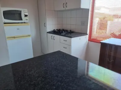 a small kitchen with white cabinets and a microwave at 3 On Herschell in Strand