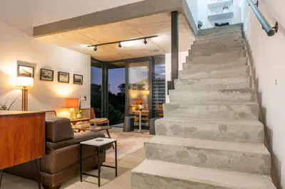 an open living room with stairs and a couch at The Glass House Loft in Bettyʼs Bay