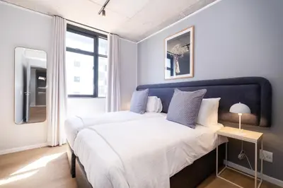 a bedroom with a large bed with a blue headboard at 504 Riverlands - Lux 2 Bedroom Apartment with Parking in Cape Town