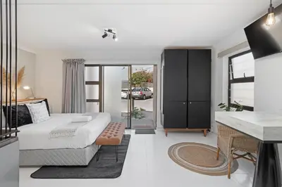 a bedroom with a bed and a desk in a room at San Norina Gardens 5 in Cape Town