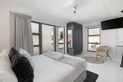 a bedroom with a white bed and a table with a chair at San Norina Gardens 5 in Cape Town