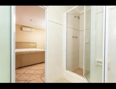 a glass shower in a room with a couch at Peters Place