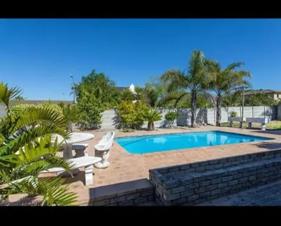 a swimming pool in a yard with two chairs at Peters Place