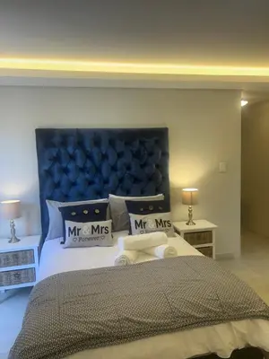 a bedroom with a large bed with a blue headboard at Immaculate,Alttrative &Modern 6 minutes away from the beach in Cape Town