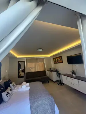 a bedroom with a large bed and a couch at Immaculate,Alttrative &Modern 6 minutes away from the beach in Cape Town