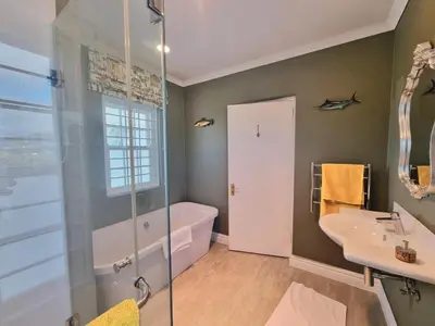 a bathroom with a shower and a tub and a sink at Moonlight in Hermanus