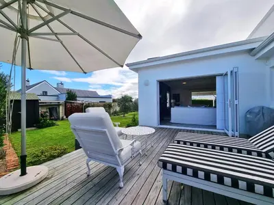 a white chair and an umbrella on a wooden deck at Moonlight in Hermanus