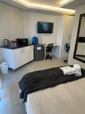 a room with a bed and a desk and a tv at Serenity suite 6 minutes away from the beach in Cape Town