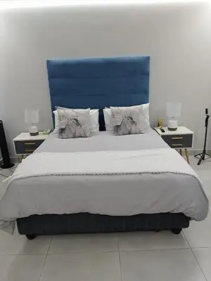 a bedroom with a large bed with a blue headboard at Serenity suite 6 minutes away from the beach in Cape Town