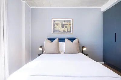 a bedroom with a large white bed with a blue headboard at 511 Riverlands - Lux 2 Bedroom Apartment with Parking in Cape Town