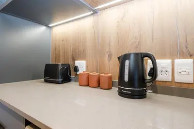 a kitchen counter with a tea kettle and cups on it at 511 Riverlands - Lux 2 Bedroom Apartment with Parking in Cape Town