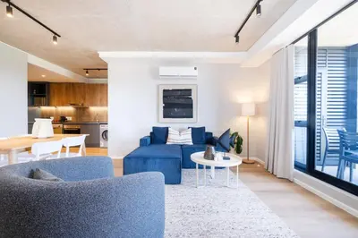 a living room with a blue couch and a table at 511 Riverlands - Lux 2 Bedroom Apartment with Parking in Cape Town