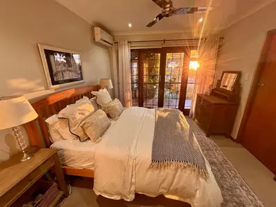 a bedroom with a bed and a table with a lamp at Family home with table mountain view and pool in Stellenbosch