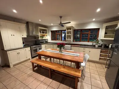 a kitchen with a wooden table and a bench at Family home with table mountain view and pool in Stellenbosch