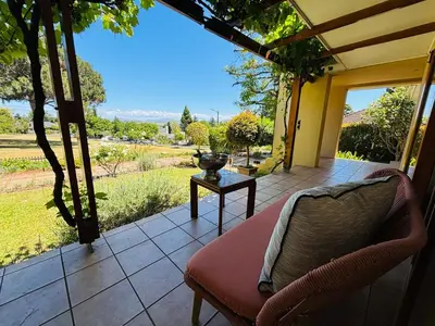 a porch with a chair and a table with a view at Family home with table mountain view and pool in Stellenbosch