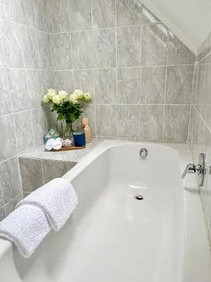 a white bath tub in a bathroom with flowers at Mountain views oasis in Franschhoek