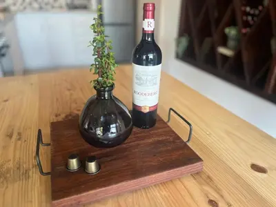 a bottle of wine and a vase on a table at Durr's Nest - Central Paarl Mountain Retreat in Paarl