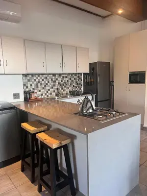a kitchen with a sink and a counter with stools at Durr's Nest - Central Paarl Mountain Retreat in Paarl