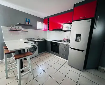 a kitchen with a white refrigerator and red cabinets at Entire Modern, Secure & Central Flat in Milnerton in Cape Town