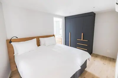 a bedroom with a white bed and a black cabinet at Ocean 9 Beachfront Residence in Cape Town