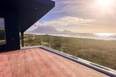 a room with a balcony with a view of the ocean at Ocean 9 Beachfront Residence in Cape Town