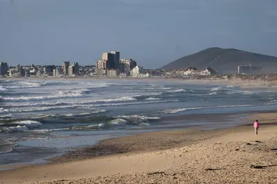 a person walking on a beach near the ocean at Ocean 9 Beachfront Residence in Cape Town