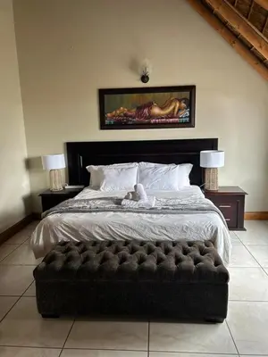 a bedroom with a large bed with a black ottoman at Daisy Accommodation & Spa in Cape Town
