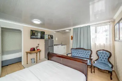 a bedroom with a bed and a chair and a table at Self Contained 2 bed Room Condo in Parow