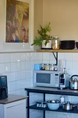 a kitchen with a microwave on a counter with dishes at The Old Dairy at Allemanskloof in Paarl