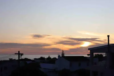 a sunset over the ocean and a city with buildings at Sunset sea views - 4 bedroom home in Hermanus