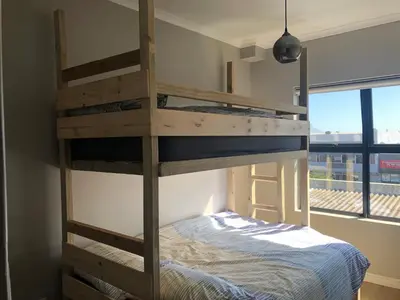 a bunk bed in a room with a bed in a room at Cape on Porterfield in Cape Town