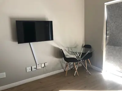 a room with a table and a television on a wall at Cape on Porterfield in Cape Town