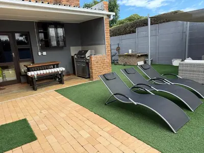 a backyard with a row of slides on a lawn at Hideaway-Poolside Comfort cottage 3km to the Beach in Cape Town