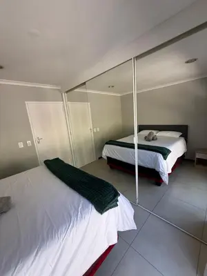 a bedroom with two beds and a mirror at Hideaway-Poolside Comfort cottage 3km to the Beach in Cape Town