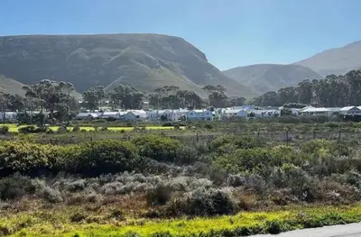 a field with houses and mountains in the background at Cali House, Kwaaiwater Getaway in Hermanus