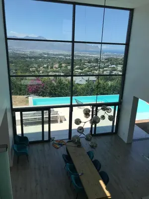 a room with a table and chairs and a large window at Luxury Family Home in Helderberg