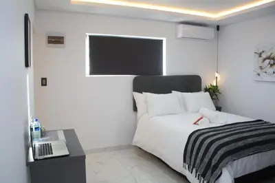 a bedroom with a bed and a desk and a laptop at Willow Brooks in Cape Town