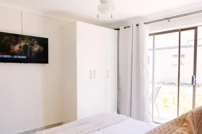 a bedroom with a bed and a tv on the wall at Vineyard Flatlets at 13 Olives Estate in Cape Town