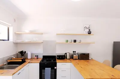 a kitchen with white cabinets and a black stove at Vineyard Flatlets at 13 Olives Estate in Cape Town