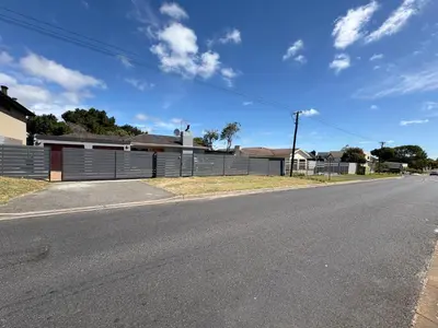 an empty street in front of a fence at Joy House in Cape Town