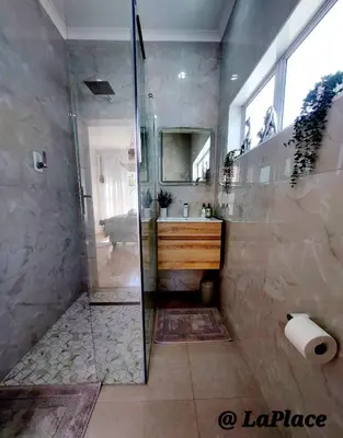 a bathroom with a shower with a sink and a mirror at LaPlace in Strand