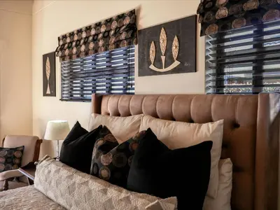 a bedroom with a brown leather bed with pillows at AFRICA WILD HERMANUS Luxury Self Catering Accommodation in Hermanus