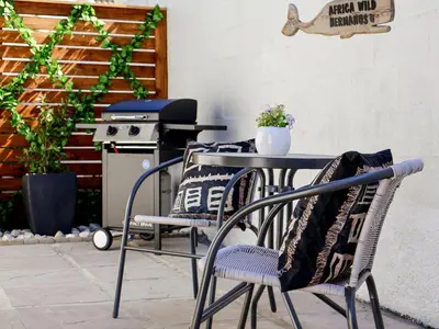 a table and chairs with a grill on a patio at AFRICA WILD HERMANUS Luxury Self Catering Accommodation in Hermanus