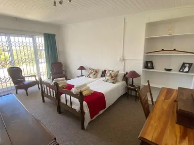 a bedroom with a bed and a table and chairs at Skurwejantjie in Hermanus