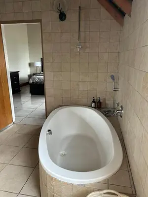 a bath tub in a bathroom with a bedroom at Daisy Accomodation and Spa 5 Bed all private en-suite in Cape Town