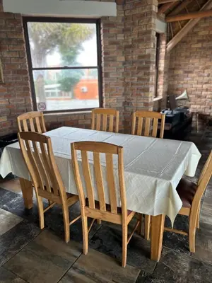 a wooden table with four chairs and a white table cloth at Daisy Accomodation and Spa 5 Bed all private en-suite in Cape Town